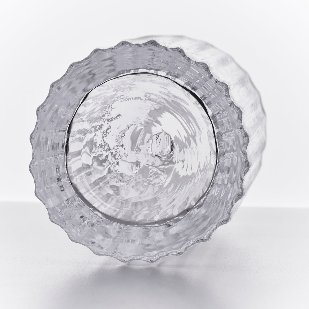 Clear glass decanter with textured wavy edges and engraved design on the bottom, shown from above.