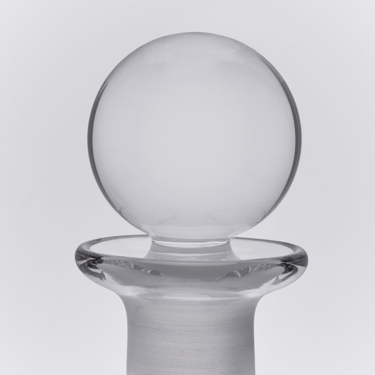 Clear glass decanter with spherical bowl top and wide cylindrical base with flared rim.