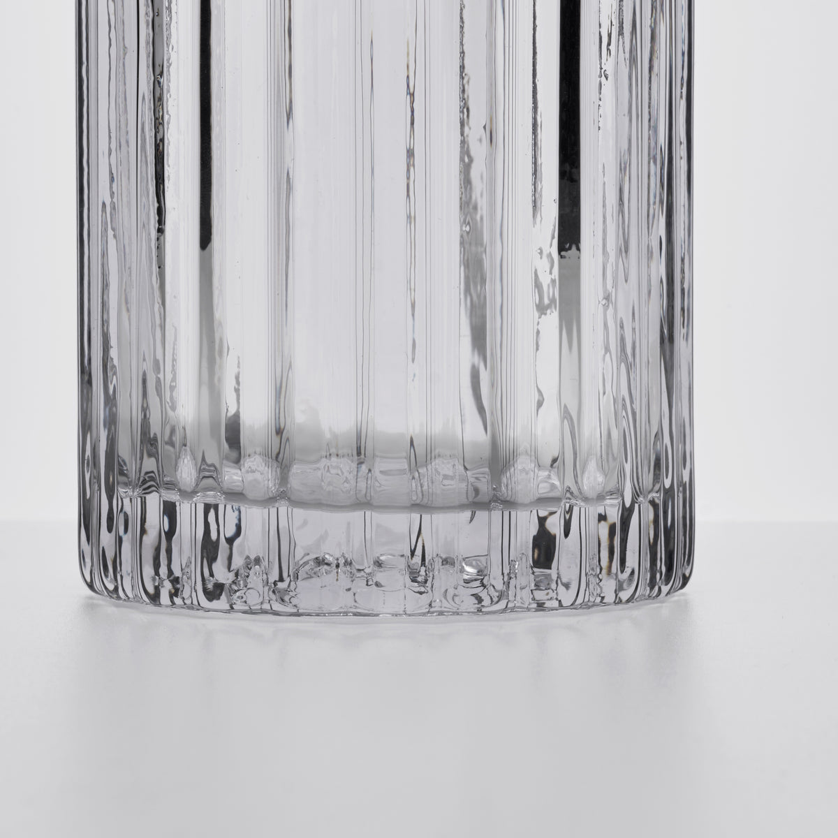 Clear glass decanter with vertical ribbed texture and rounded base, shown from above against white background.