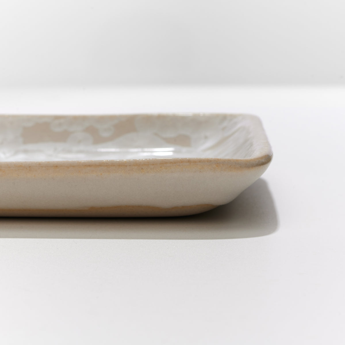 Small rectangular platter with cream-colored crystalline glaze and gently curved edges.
