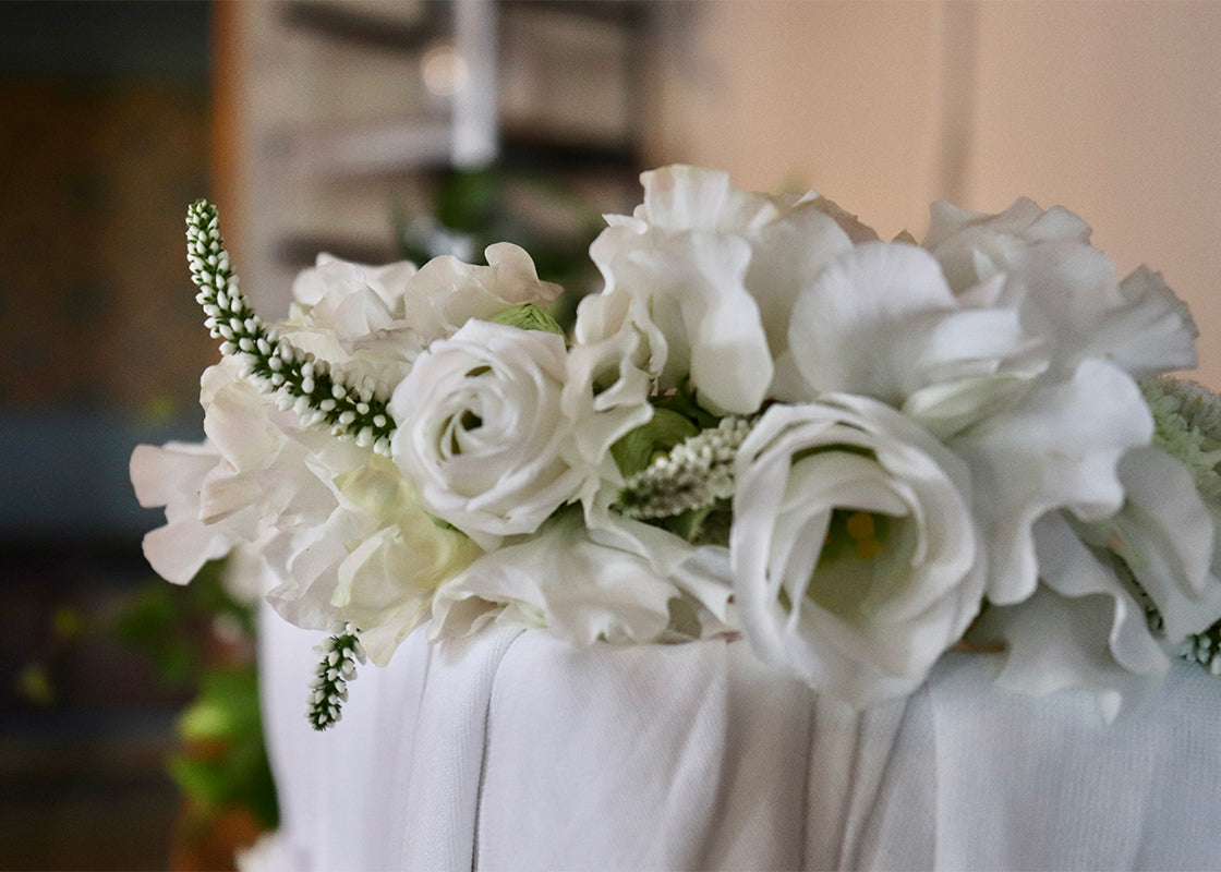Close-up of white roses and lisianthus flowers adorning a draped wedding ceremony chair