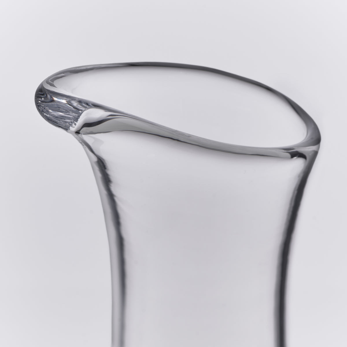 Clear glass carafe with curved sides and a pouring spout at the rim.