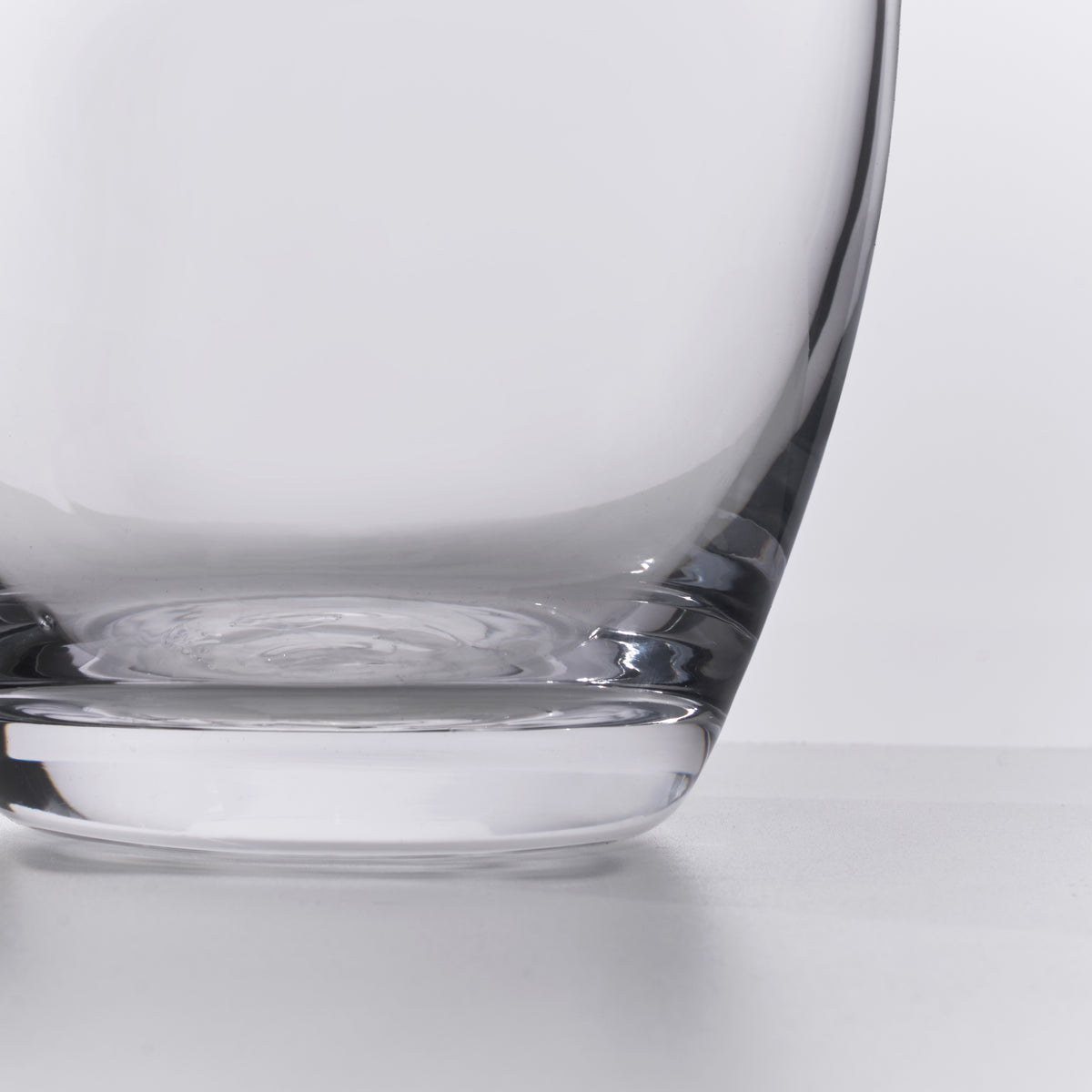 Clear glass carafe with curved walls and a wide base, shown from side angle against white background.