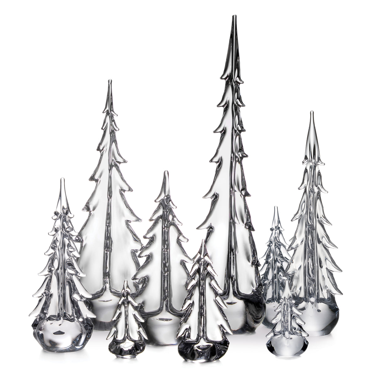 Group of seven clear glass evergreen tree figurines in varying heights with pointed tops and layered branches.