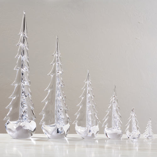 Five clear glass evergreen trees in graduating sizes with white frosted bases.