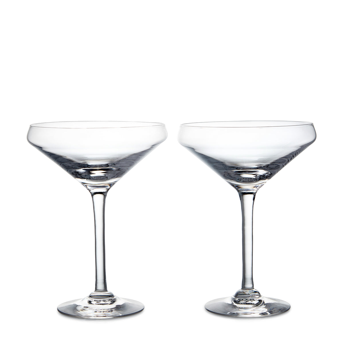 Two clear coupe glasses with wide bowls and thin stems on white background.