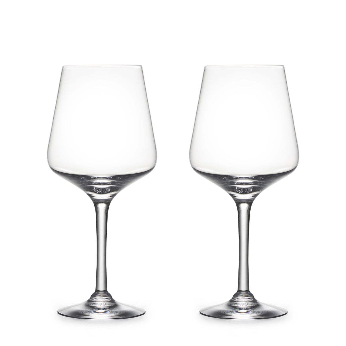 Two empty clear wine glasses with tapered bowls and thin stems on white background.
