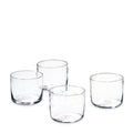 Four clear cylindrical drinking glasses with thick bases arranged in a group.