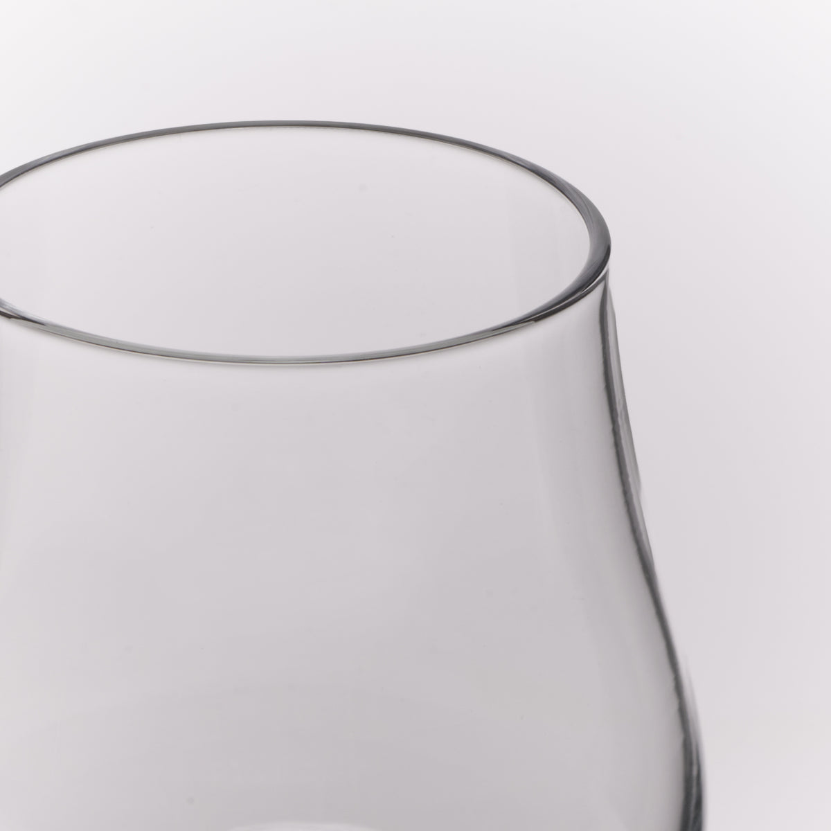 Close-up of a clear glass vessel, showing the rim and upper body against a light gray background.