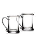 Two clear glass tankards with handles and circular base medallions.
