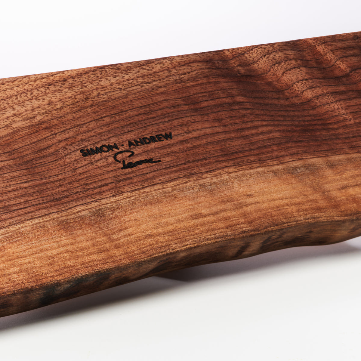 Wooden serving board with "Simon Andrew" engraved text and natural grain pattern.