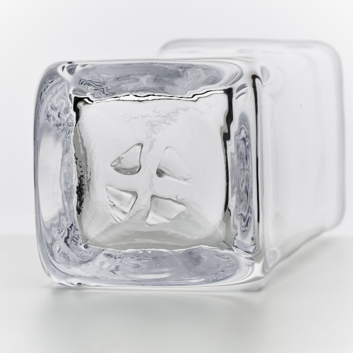 Clear glass carafe with ice cubes inside and a handle on the side.