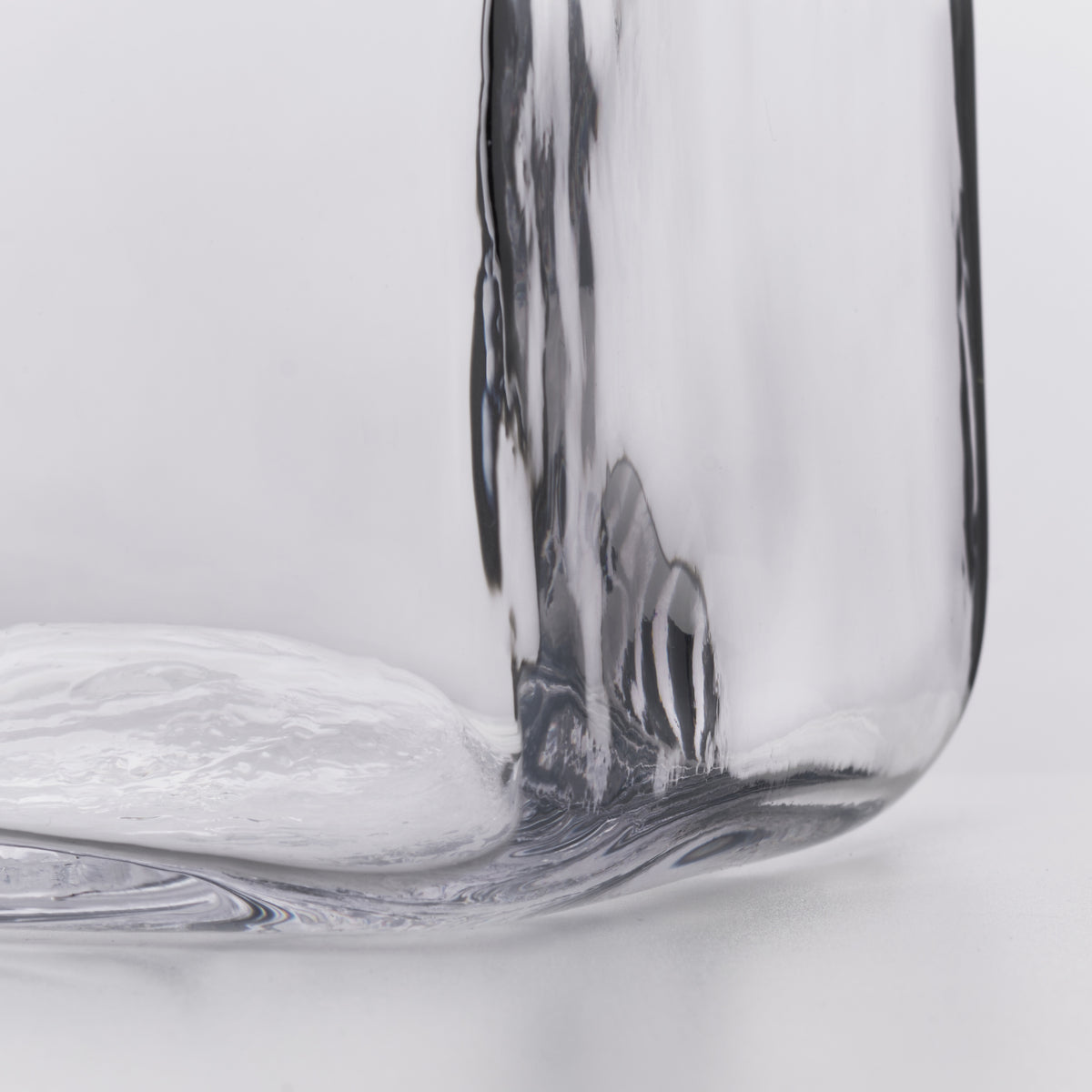 Clear glass decanter with curved sides and a rounded base against a white background.
