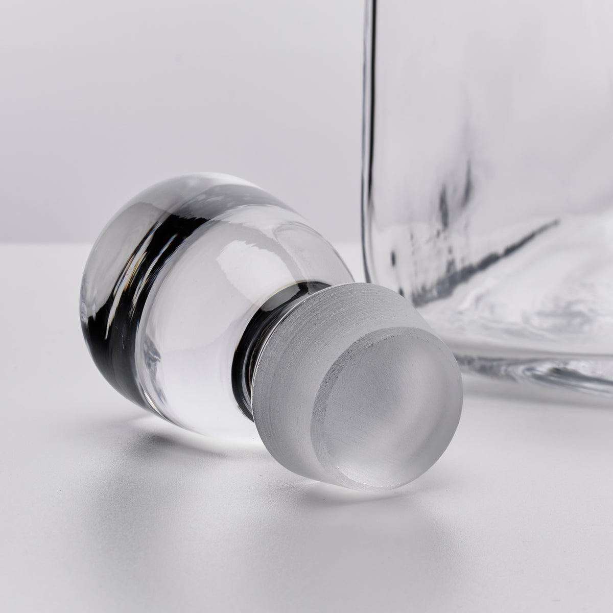Clear glass decanter with a frosted stopper and black metal bands around the neck.