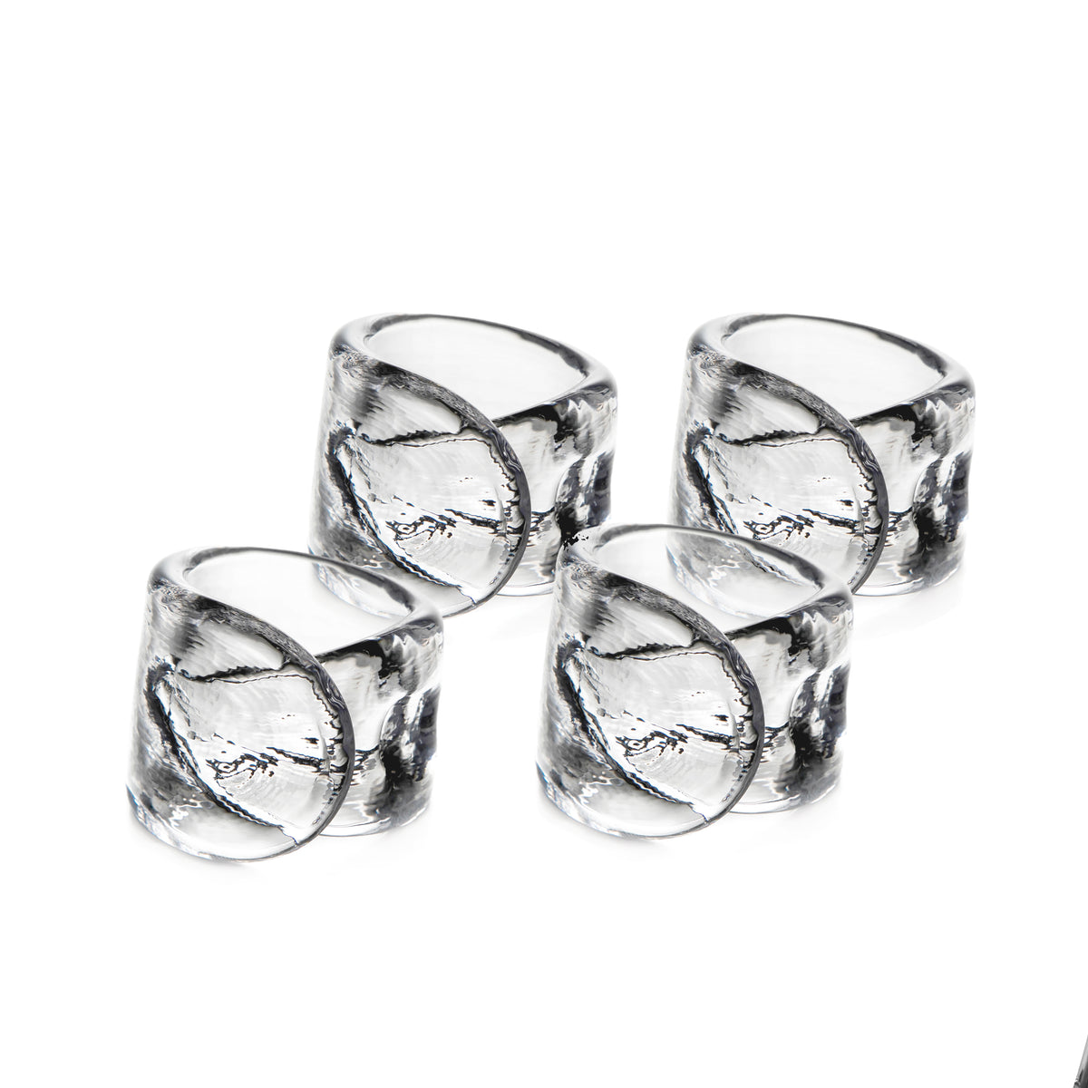 Four clear glass napkin rings with leaf-etched design arranged in two rows.