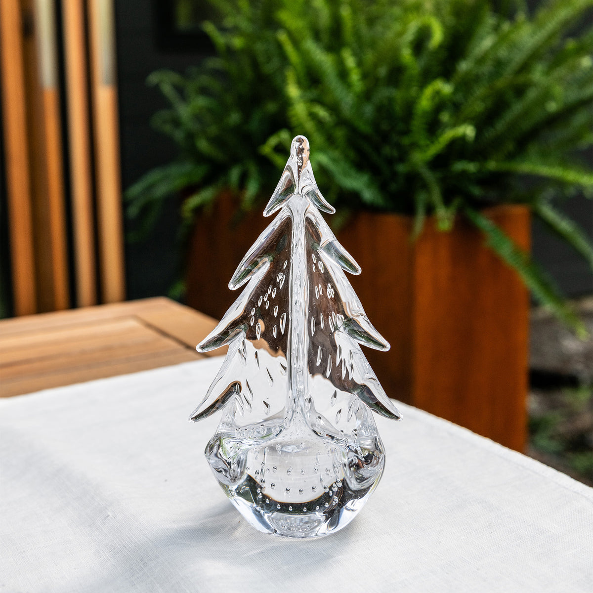 Clear glass evergreen tree figurine with textured details on white surface.