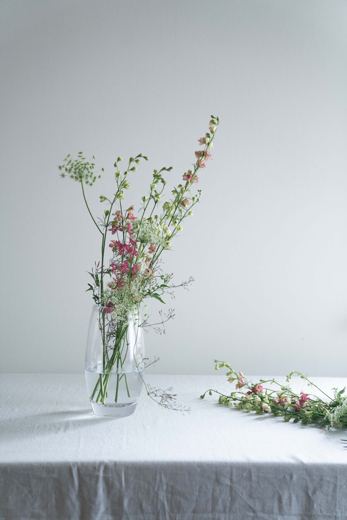 Clear glass vase with mixed dried flowers and greenery arranged inside, including pink blooms and delicate stems.