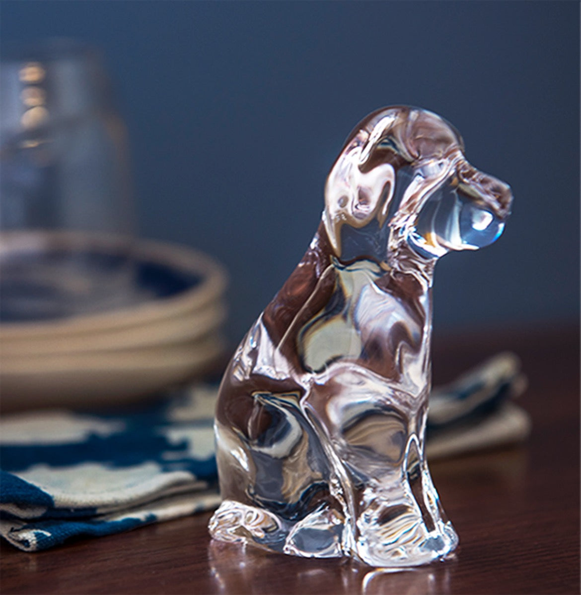 Clear glass dog figurine with brown and white coloring, sitting upright on a wooden surface.