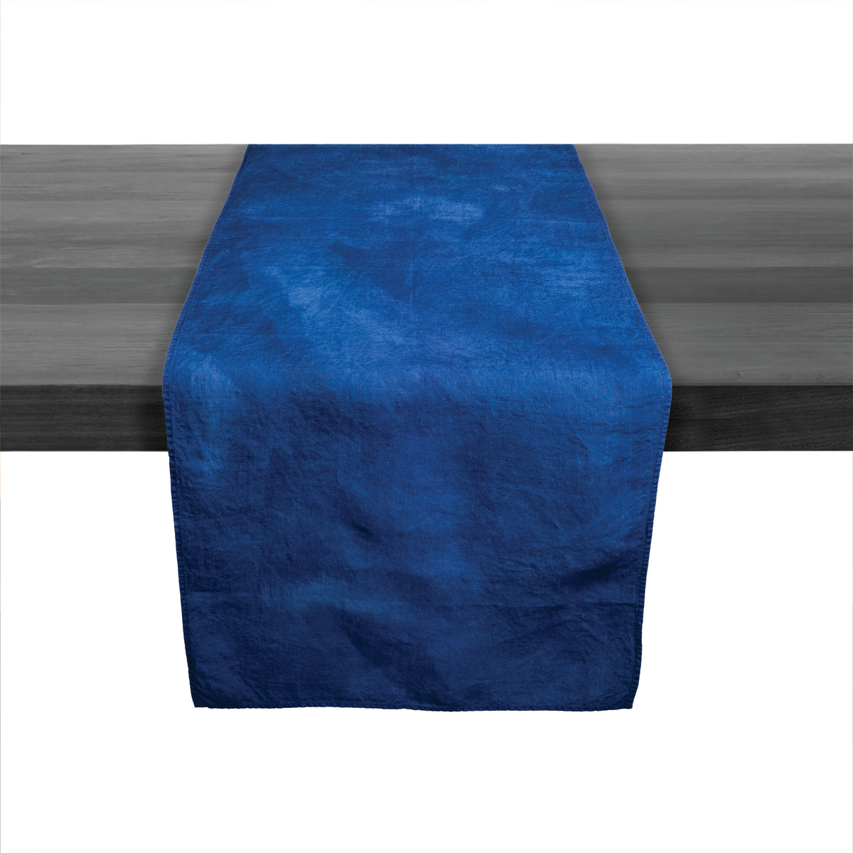 Deep indigo linen table runner with textured surface displayed on dark wood table.