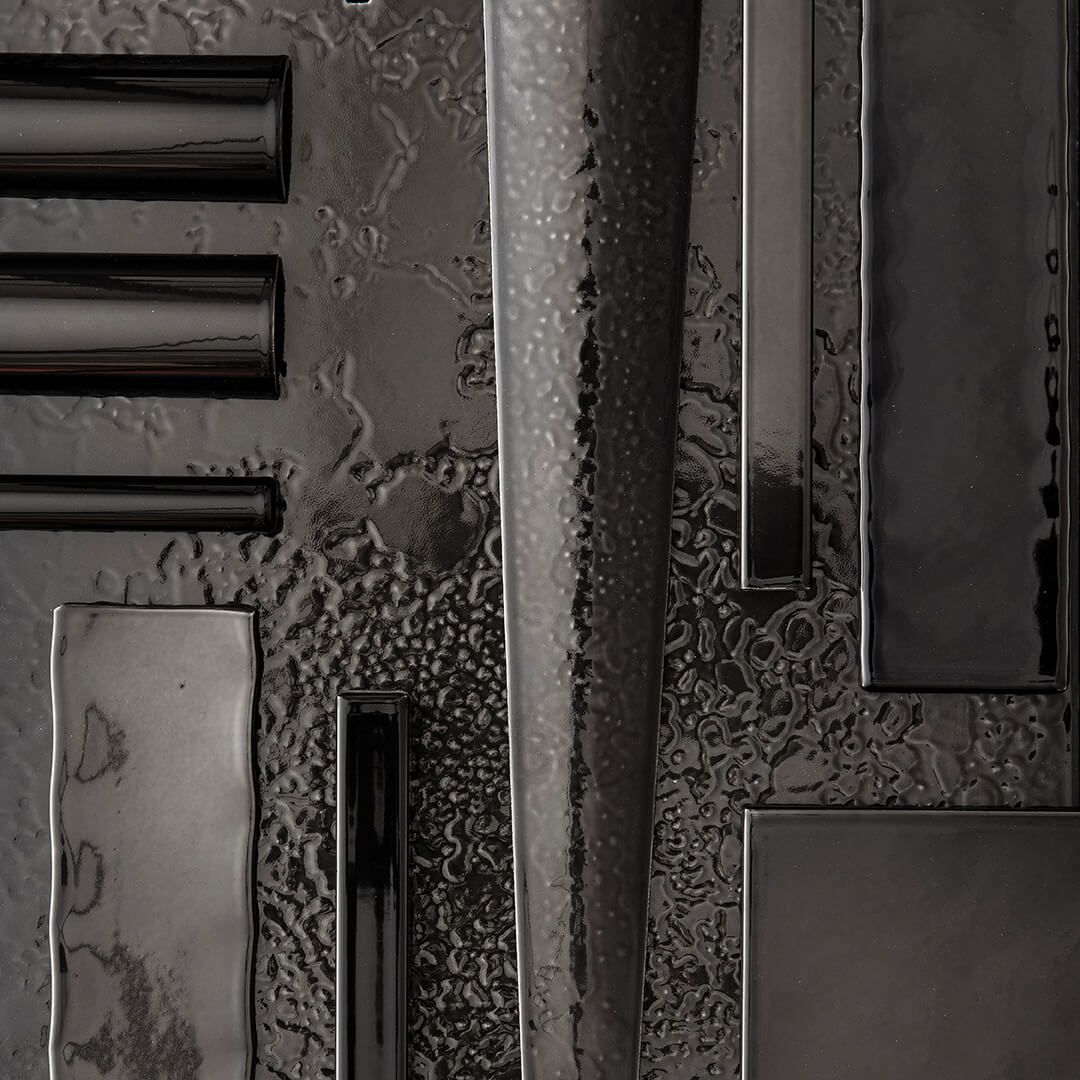 Black metal cylindrical tubes and rectangular panels arranged vertically against textured gray wall.