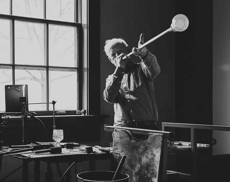 Simon Pearce blowing molten glass on a blowpipe in his Vermont workshop