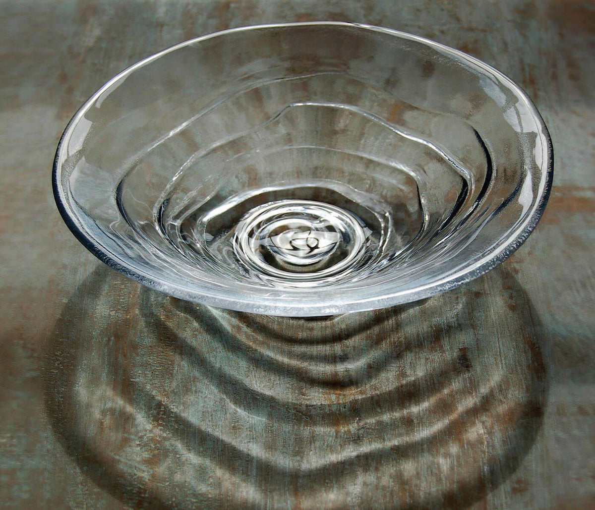 Clear glass bowl with concentric ripple pattern and water droplet detail inside.